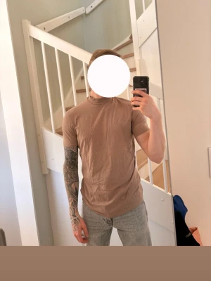 Beige basic t-shirt i bomull - En enkel beige t-shirt med rund hals och korta ärmar. Tillverkad i mjuk bomull och har en normal passform. Perfekt till jeans eller shorts för en clean och avslappnad look.