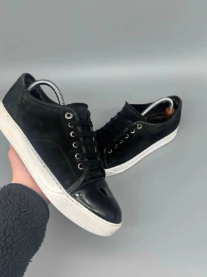 Lanvins skor - Snygga svarta sneakers med ovandel i mocka och detaljer i blankt lack framtill. Skorna har vita sulor, svarta skosnören och metallfärgade öljetter. Perfekta för en stilren och trendig look.