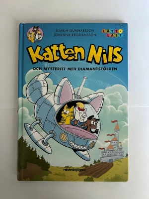Katten Nils och mysteriet med diamantstölden - En färgglad och rolig barnbok med hårda pärmar, illustrerad av Joakim Gunnarsson och Johanna Kristiansson. Boken har ett blått och lila omslag med tecknade katter i ett rymdskepp och ett slott i bakgrunden. Perfekt för dig som gillar lättlästa äventyr.