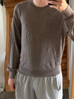 Brun stickad tröja i 100% ull - Brun stickad tröja i 100% merinoull. Storlek L men passar mer M. Modellen är 183 och väger 72 kg. 