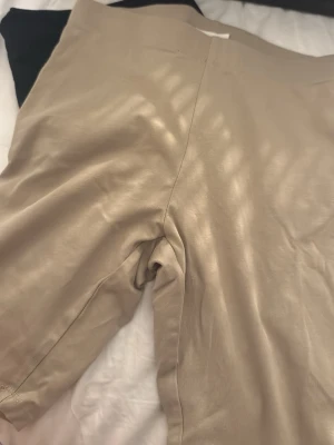 Beiga och svarta  cykelbyxor i bomull - Två par shorts, ett par i beige och ett par i svart. Båda har enkel design och är tillverkade i mjukt bomullsmaterial med elastisk midja för skön passform. Perfekta för varma dagar och chill outfits.