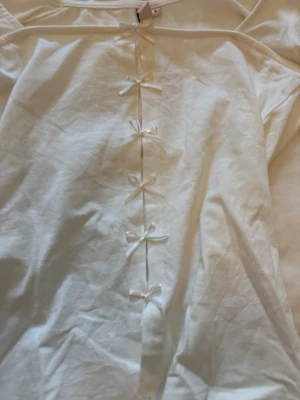 Långärmad tröja med rosetter - Säljer denna super söta och helt nya långärmade tröjan från Nelly med rosetter. Helt ny med prislapp kvar. Endast testad💕