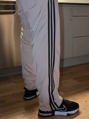 Beige Adidas loungewear dress helt nu Smal  - Säljer ett beige loungewear set från Adidas med klassiska svarta ränder på ärmar och ben. Setet består av en ziptröja med hög krage och matchande byxor med dragsko i midjan. Båda delarna har Adidas logga framtill. Perfekt för chill dagar hemma. Helt ny nypris stadium 849 och mjukis 700 säljes för tusen  sitter riktigt snyggt med mjuka 