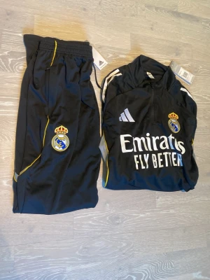 Real Madrid träningsset Adidas svart - Tja! Säljer ett par helt nya Real Madrid tracksuit. Det går att köpa bara en av dem också.                   Storleken är Medium och kvaliteten är precis som nya. Priset kan diskuteras och skickar inom 24 Tim ☺️💨