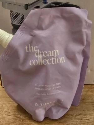 Rituals Fluffy Body Scrub Dream " limited edition" - Ljuslila body scrub från Rituals, The Dream Collection. Kommer i en mjuk påse med vit text. Doft av blue daisy och moonstone. Perfekt för dig som vill ha en lyxig och fluffig kroppspeeling. 220 ml
