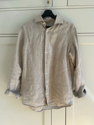 Beige linneskjorta från La Chemise - Säljer denna snygga linneskjorta från La Chemise! Skjortan är i en snygg nyans av beige som passar till mycket och i str 40 vilket är M. Köpt för 900kr på Norrmalm och använd 4 gånger. Hör gärna av er vid frågor eller funderingar!