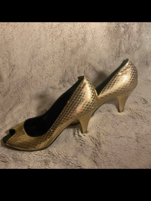 Guldiga peep toe-pumps med ormmönster  - 🌸Guldiga peep toe-pumps med ormmönster ✔️Märke: Tesori                                                       📏Storlek: 36                                                 ❗️Använt skick. Slitage på klackar, innersulor och yttermaterial samt bruksspår enligt bilderna.
