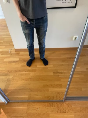 Blå raka jeans från Levi's L30 - Säljer ett par klassiska blå jeans från Levi's med rak passform och normal midja. Jeansen har fem fickor, diskreta slitningar och den ikoniska röda Levi's-lappen på bakfickan. Perfekta till en avslappnad stil och tillverkade i slitstark denim.