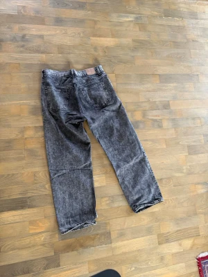 Gråa raka jeans från Weekday - Säljer ett par gråa raka jeans från Weekday, modell Galaxy Loose Straight Jeans. Jeansen har en tvättad look, fem fickor och är tillverkade i bomull. Perfekta för en avslappnad och trendig stil.