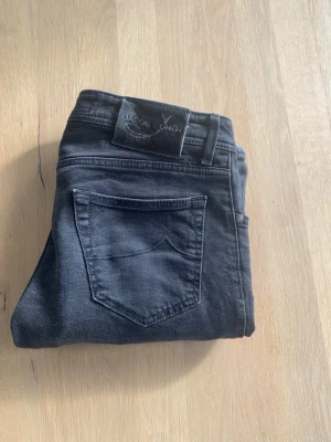 Jacob cohën jeans - Snygga svarta jeans från Jacob Cohën med klassisk femficksdesign och raka ben. Jeansen har en diskret tvättad look och är tillverkade i stretchigt denim för en bekväm passform. Perfekta för en stilren och modern look.