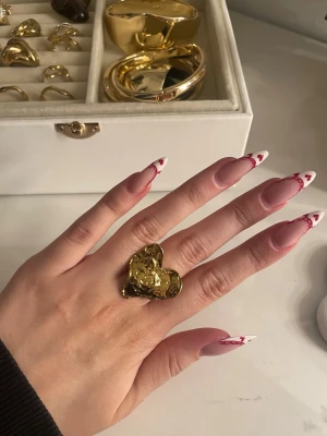 Guld ring - Säljer denna guldpläterade hjärt ring från pilgrim. Ringen är justerbar så man behöver inte tänka på någon storlek. Den är ifrån en gammal kollektion så den säljs inte längre!