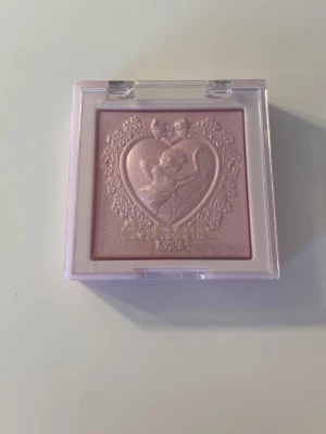 Dasique Luxe Glow Highlighter Ice Lavender - Superfin highlighter från Dasique i nyansen Ice Lavender. Kommer i en ljuslila fyrkantig dosa med genomskinligt lock och ett sött ängelmotiv i pudret. Ger en skimrande lavendellila glow till huden. Har ej använts utan bara swatchats på handen! 