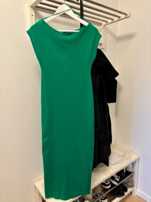 Grön långklänning från Zara - Snygg grön långklänning från Zara med enkel och stilren design. Klänningen har en rak passform och är ärmlös, vilket ger en modern och clean look. Perfekt för dig som gillar minimalistisk stil och vill sticka ut med färg.