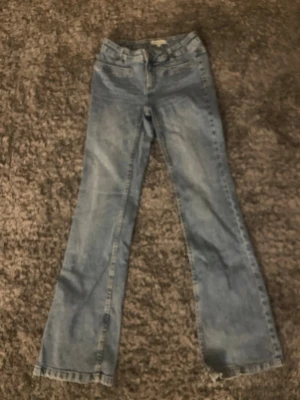 Ljusblå bootcut jeans från Lindex - Säljer ett par ljusblå bootcut jeans från Lindex med klassisk femficksdesign och bälteshällor. Jeansen har en lätt tvättad look och raka, utsvängda ben. Perfekta för en avslappnad och trendig stil.