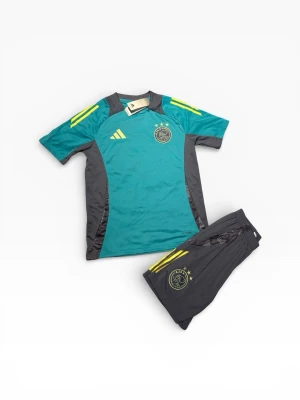Ajax träningsset från Adidas - Säljer ett Ajax träningsset från Adidas med t-shirt och shorts. Tröjan är turkos med gråa sidopaneler och gula detaljer på axlarna. Både tröja och shorts har Ajax-loggan och Adidas-loggan. Materialet är lätt och andas, perfekt för fotbollsträning.