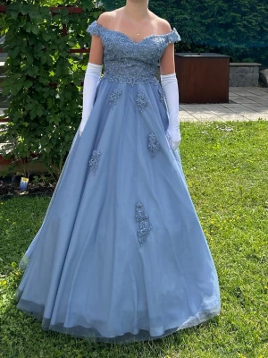 Blå balklänning med spetsdetaljer - Säljer min balklänning då den inte används. Jag köpte den begagnad, använd 2 gånger. Den är i fint skick och passar en S/liten M. Man får med underkjol och handskar. (Pris går att förhandla vid snabb affär)