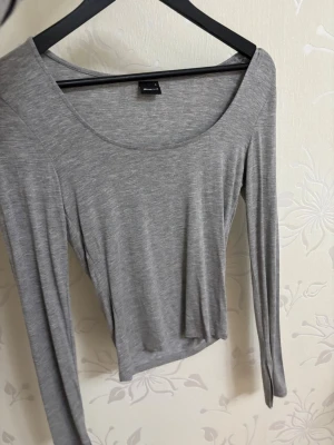 Tre långärmade toppar från Gina - Säljer tre basic långärmade toppar från Gina , en i grått, en i grönt och en i mörkblått. Båda har rundad, bred urringning och är tillverkade i mjuk bomullsmix. Samt med en slits i ärmarna. Perfekta att styla med jeans eller kjol för en enkel och clean look. (Säljs i tre pack!)