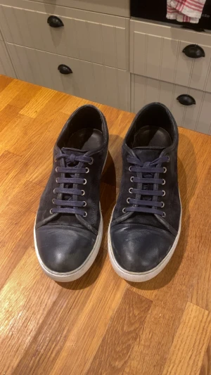 Mörkblå låga sneakers i läder - Snygga mörkblå sneakers med lågt skaft och matchande blå skosnören. Skorna har en vit sula och är tillverkade i läder för en clean och stilren look. Perfekta till jeans eller chinos för en avslappnad vibe.