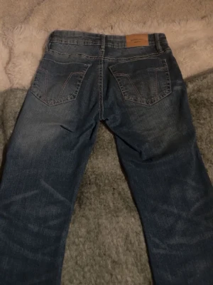 Lågmidjade bootcut jeans - Säljer ett par blå bootcut jeans från gina. Jeansen har kontrastsömmar på bakfickorna. Använda ett fåtal gånger.