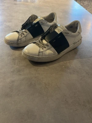 Valentino open mörkblå - Snygga vita sneakers från Valentino. Modell open mörkblå. Ganska bra skick lite slitage här och där men uppnår fortfarande funktionen till 100%. Sulorna är med slitna men fortfarande mycket att ge. (Kartong och påse kan fixas)
