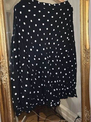 Svart prickig långkjol från H&M - Svart långkjol från H&M med vita prickar. Kjolen har en luftig och flowy passform. 