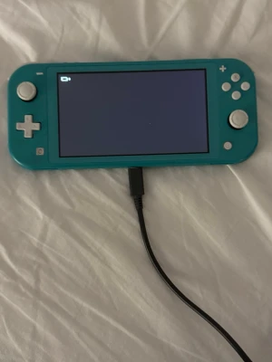 Turkos Nintendo Switch Lite konsol - Säljer en turkos Nintendo Switch Lite, en smidig och portabel spelkonsol med inbyggda knappar och styrkors. Perfekt för gaming på språng och enkel att ta med sig. Laddas via USB-C och har en matt plastfinish.