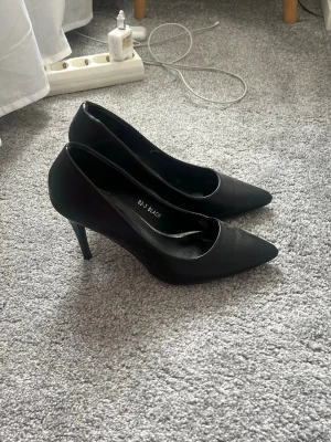 Svarta klassiska klackar med smal klack - Säljer ett par svarta pumps klackskor med spetsig tå och smal hög klack. Skorna har en stilren och tidlös design, perfekta för att lyfta vilken outfit som helst. 