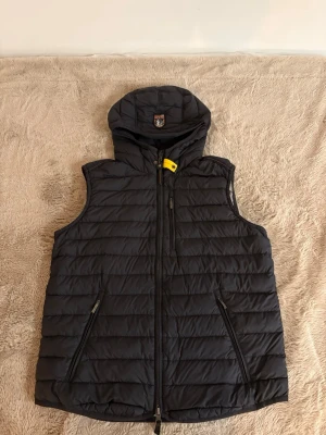 Svart dunväst från Parajumpers - Säljer en svart dunväst från Parajumpers med huva och klassisk logga på ryggen. Västen är sparsamt använd ser ny ut! 