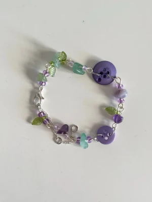 Somrigt lila armband - Handgjort armband i silver med lila tema. Unikt och gjort med återbrukade knappar. Skriv vid fler frågor eller funderingar💞
