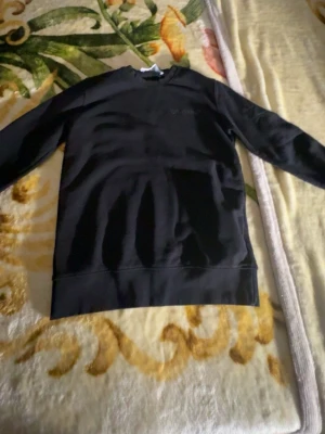 Svart hoodie från Off-White - Säljer en svart hoodie från Off-White med diskret broderad logga på bröstet. Hoodien har klassisk passform, lång ärm och stor magficka framtill. Tillverkad i mjukt bomullsmaterial som känns skönt mot huden. Perfekt för dig som gillar streetwear och stilrena plagg. Helt ny inte ens använt.