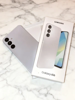 Samsung Galaxy A16 silver, 128GB - Samsung Galaxy A16 i snygg silverfärg med stilren design och rundade hörn. Telefonen har tre kameror på baksidan och en stor skärm. Tillverkad i plast och glas, perfekt för dig som gillar modern och enkel look.