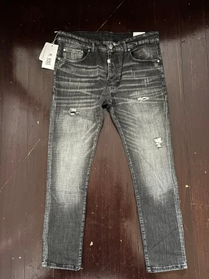 Grå slitna jeans från Horseist - Säljer ett par grå jeans från Horseist med skinny fit och slitna detaljer på både fram- och baksida. Jeansen har fem fickor, knappgylf och cool tvättad look med ljusare partier. 