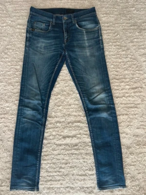 Blåa jeans ”Made in Italy” - Snygga blå skinny jeans med lätt slitna detaljer och klassisk femficksdesign. Jeansen har en smal passform och normal midja, perfekta för en trendig och avslappnad look. ”Made in Italy” helt oanvända 32/32 strl. Kan gå ner i pris vid snabb affär.