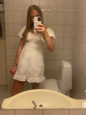 Vit kort klänning med puffärm - Klänningen har broderade blommor över hela tyget och en v-ringad urringning. Endast använd två gånger!