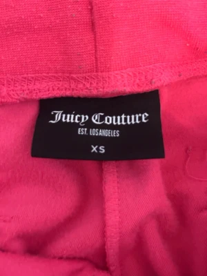 Juicy Couture rosa velourbyxor XS - Säljer ett par klassiska rosa velourbyxor från Juicy Couture i storlek XS. Byxorna har broderad JC-logga vid fickan.