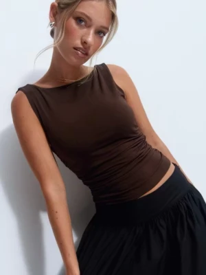 Helt ny draperad topp med öppen rygg - Snygg brun ärmlös topp med tight passform och draperad öppen rygg. Helt ny, oanvänd med prislapp kvar från Gina Tricot. Tillverkad i mjukt och stretchigt material som sitter skönt mot kroppen. Perfekt att styla med kjol eller jeans för en trendig look.