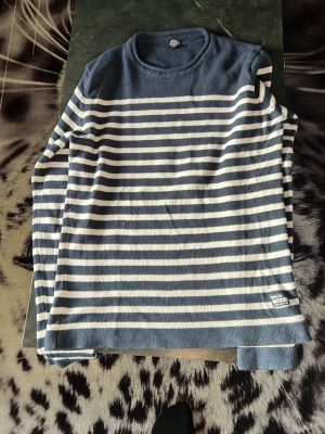 Marinblå randig stickad tröja S - Säljer en marinblå stickad tröja från On Our Terms med vita horisontella ränder. Tröjan har rund halsringning och långa ärmar. Perfekt för dig som gillar klassisk och avslappnad stil. Materialet känns mjukt och bekvämt mot huden.