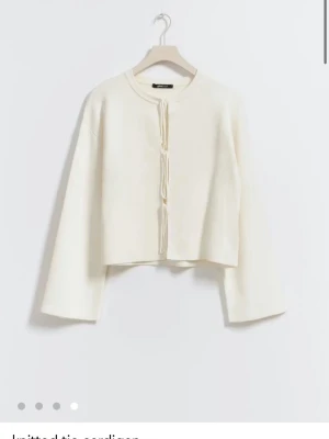 Vit kofta med knytband från Gina Tricot//kostar egentligen 400kr// säljer också en i grå - Trendig vit kofta från Gina Tricot med långa ärmar och knytband framtill. Koftan har en rak, något kortare passform och är tillverkad i mjukt stickat material. Perfekt att slänga över en topp för en clean och stilren look. 