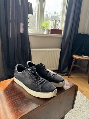 Vagabond skor - Snygga svarta sneakers i mocka med klassisk vit sula och svarta skosnören. Modellen är låg och passar perfekt till en avslappnad streetstil. Skorna har en stilren design utan synliga loggor och ger en clean look till outfiten. Mockan är i bra skick.