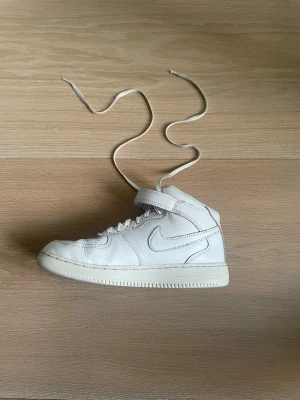Vita Nike Air Force 1 Mid sneakers - Nike Air Force 1 – vita (strl 35)  Säljer ett par klassiska Nike Air Force 1 i vitt. Använda men fortfarande i okej skick.  ✔️ Bekväma och passar till allt  OBS: Det finns ett mindre hål i ena skon (se bild), samt vanligt slitage/crease.   Skriv vid frågor eller fler bilder