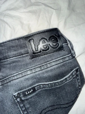 Grå Lee jeans med raka ben - Säljer ett par grå jeans från Lee med raka ben och klassisk femficksdesign. Jeansen har en snygg tvättad look och Lee-logga på bakfickan samt bakre linningen. Perfekta för dig som gillar en avslappnad och tidlös stil. Storlek size 25 längd 30 använda 2 gånger bara så de är som nya köpta för 1000kr.