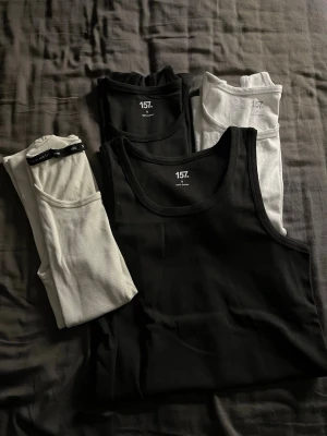 Svarta och vita linnen från 157 - Säljer ett set med svarta och vita linnen från 157. Linnena har klassisk rund halsringning och är tillverkade i mjuk bomull. Perfekta att bära som lager eller för en clean och enkel stil.