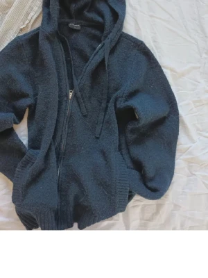 Mörkblå zip hoodie med luva - Mysig mörkblå hoodie med dragkedja och luva. Tröjan har ribbade muddar, fickor framtill och justerbara snören i luvan. Perfekt för chill dagar och enkel att matcha med jeans eller mjukisbyxor.