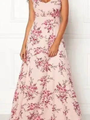 Lång blommig klänning med v-ringning - Romantisk långklänning i ljusrosa med blommigt mönster i rosa och vinröda toner. Klänningen har v-ringning både fram och bak samt är ärmlös. Perfekt för sommarens alla tillfällen och har en svepande, elegant siluett.