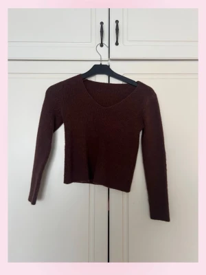 Brun ribbstickad tröja med v-ringning - 💕Mysig brun stickad tröja med v-ringad hals och långa ärmar. Tröjan har en kroppsnära passform och är ribbstickad för extra stretch och komfort. Perfekt att matcha med jeans eller kjol för en enkel och snygg look.💗
