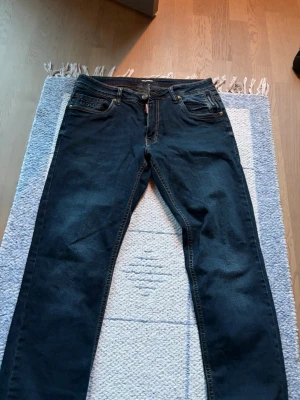 Mörkblå jeans från Dsquared2 - Snygga mörkblå jeans från Dsquared2 med klassisk femficksmodell och kontrastsömmar. Jeansen har en rak passform och detaljer som röd logotagg vid gylfen. Perfekta för en trendig och avslappnad stil.