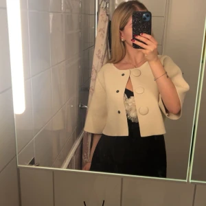 Krämvit cardiganjacka från ZARA - Snygg krämvit cardiganjacka från ZARA med stora knappar framtill och trekvartsärmar. Jackan är stickad i ett mjukt material och har en rak, boxig passform. Perfekt att slänga över en klänning eller topp.