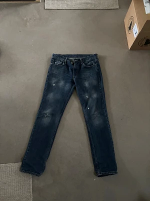 Mörkblå Levi's jeans med slitningar - Säljer ett par mörkblå jeans från Levi's 511 med klassisk femficksmodell och raka ben. Jeansen har snygga slitningar framtill för en trendig look och är tillverkade i denim. Perfekta för dig som gillar en avslappnad men stilren stil. Och storleken är w32 och L34