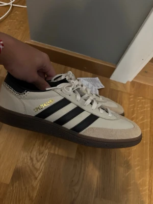 Adidas spezial  - Säljer ett par Adidas spezial sneakers med klassiska tre ränder på sidan och guldfärgad spezial-text. Ovandelen är i läder och mocka, yttersulan är brun och skorna har vita snören. Perfekta för dig som gillar retrostil och streetwear.