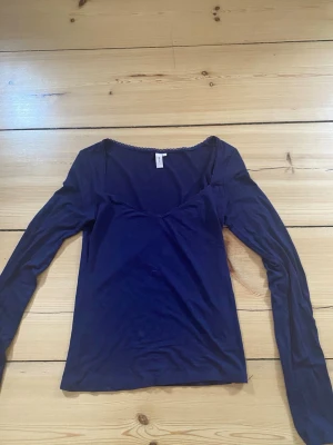 Mörkblå topp med urringning och spetskant längst kantenfrån Nelly - Mörkblå långärmad topp från Nelly med en fin urringning 